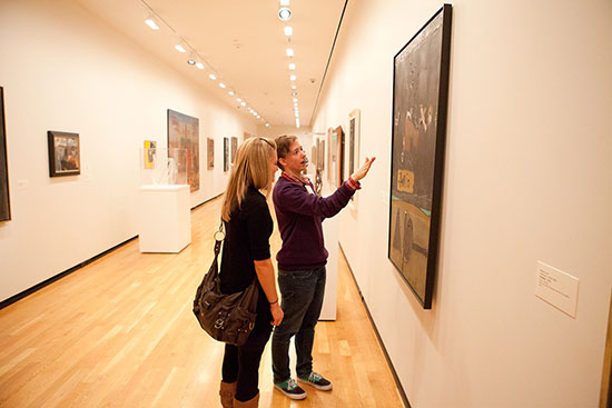 Photo from a project called See for Yourself depicting a guide describing a piece of art to a person who is closing their eyes.
