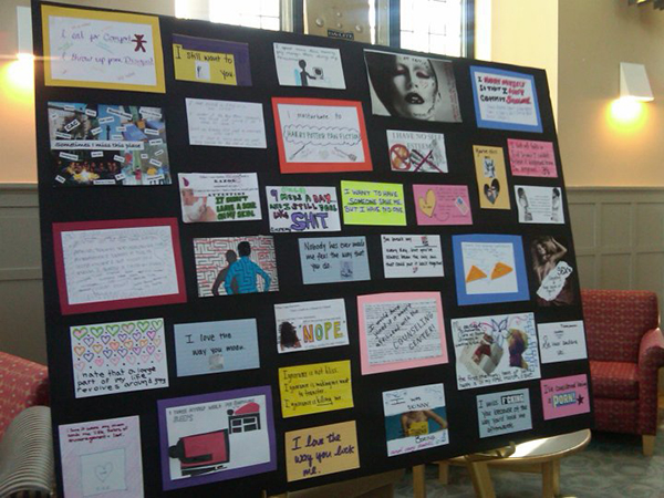 A black poster board, featuring an arrangement of post secrets, in many different shapes and colors, on display in Bryn Mawr's campus center.
