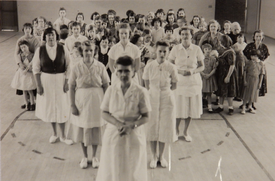 Black and white photograph showing a number of women and children in what appears to be a gymnasium