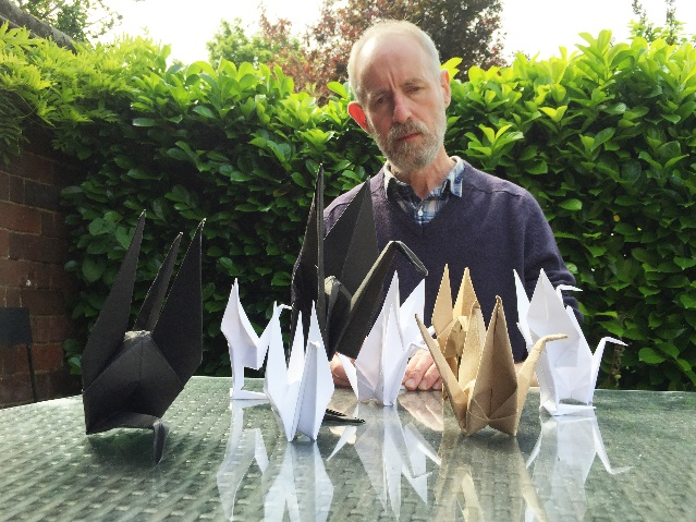 David Johnson sitting at a table with paper cranes.